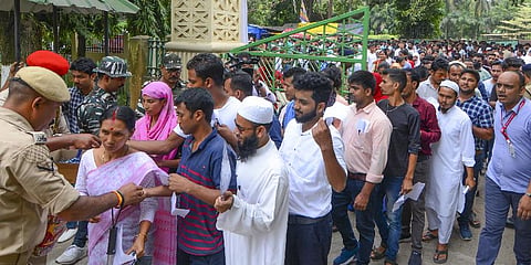 Aspirants arrive to appear in a written examination for Assam State Level Recruitment for Class III and IV posts, at Cotton University in Guwahati. (Photo | PTI)