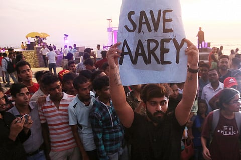 An activist holds a placard during a protest against cutting down of trees for a proposed metro car shed project at Aarey Colony in Mumbai, July 2022.| (Photo | PTI)