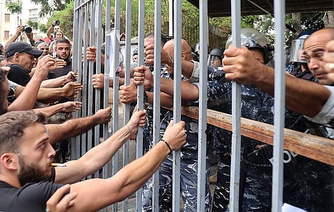 Protesters try to pull out the gate leading to the Justice Palace in Lebanon's capital Beirut on September 19, 2022, demanding the release of two people involved in a bank heist. (AFP)