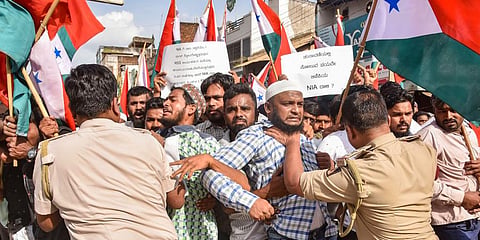 Police attempt to detain PFI and SDPI workers during a protest against the raid of NIA.(Photo | PTI)