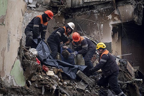 Rescue workers transfer the body of a man killed in a Russian missile strike on an apartment building, into a plastic bag in Ukraine.