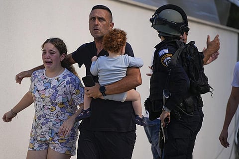 Israeli police officers evacuate a family from a site hit by a rocket fired from the Gaza Strip, in Ashkelon, southern Israel. (Photo | AP)