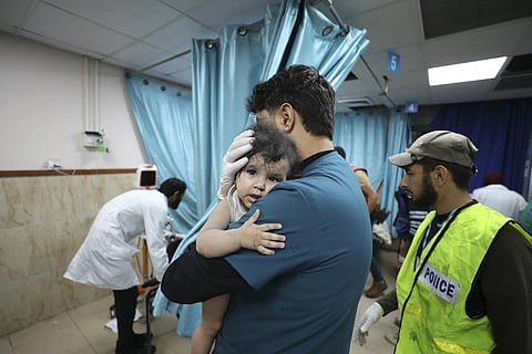 Palestinian medic holds a child wounded in Israeli airstrike on the Gaza Strip, in Deir-el Balah, Sunday, Oct 22, 2023. (Photo | AP)