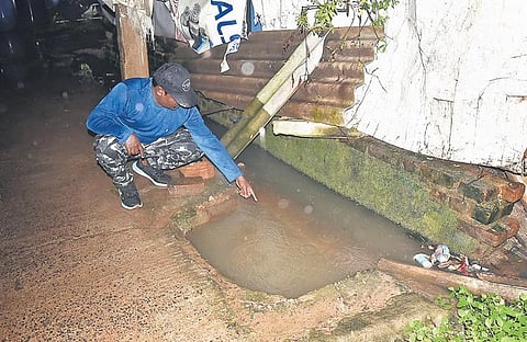 A resident pointing out the metrowater tap in the pit that got submerged after heavy rain at Korattur in Chennai. (Photo | P Ravikumar, EPS)