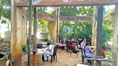 Hospital staff seen working under an overhead tank at the PHC in Pallamkurru village in Konaseema district | EXPRESS