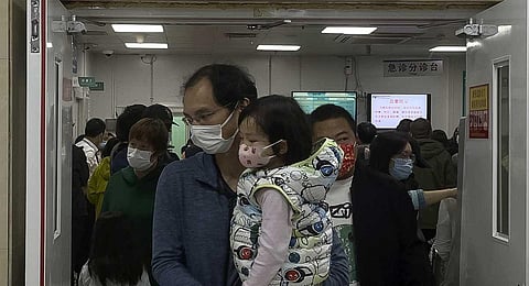A man carriers a child walk out from a crowded holding room of a children's hospital in Beijing on Oct. 30, 2023. (AP)