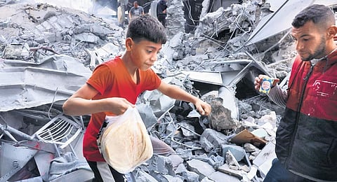 A Palestinian youth carries bread amid the rubble in the Gaza Strip.(File Photo | AFP)