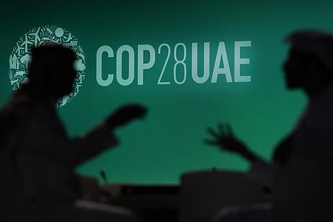 FILE - People are silhouetted against a logo for the COP28 UN Climate Summit, Nov. 29, 2023, in Dubai, United Arab Emirates. (Photo | AP)