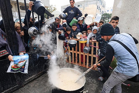Palestinians wait to collect food at a donation point in a refugee camp in Rafah in the southern Gaza Strip on December 23, 2023. (Photo | AFP)