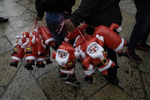 People hold Santa Claus balloons on Christmas Eve, near the Church of the Nativity, in the West Bank city of Bethlehem. (Photo | AP)