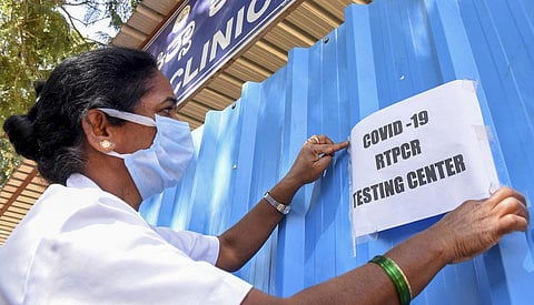 A medic puts up a notice at a Covid-19 testing centre of the district hospital after cases of COVID-19 sub-variant JN.1 were detected. (Photo | PTI)