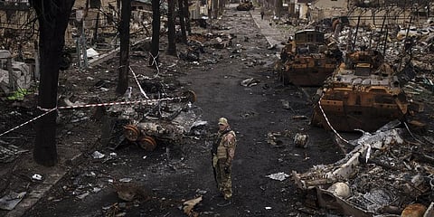 A Ukrainian serviceman stands amid destroyed Russian tanks in Bucha, on the outskirts of Kyiv.
