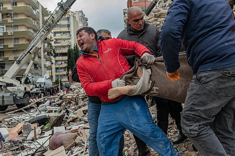 A rescuer in Turkey reacts as he carries a body found in the rubble in Adana on February 6, 2023, after a 7.8-magnitude earthquake struck the country's south-east. (Photo | AFP)