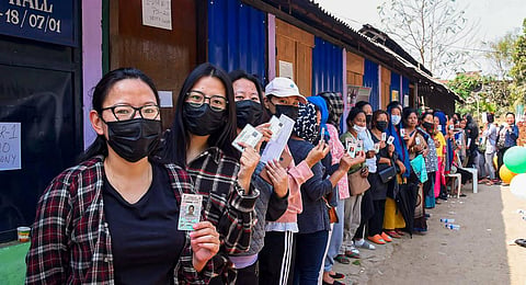 Voters standing in a queue show their ID cards before casting their votes for the Nagaland Assembly election, at a polling booth in Dimapur.
