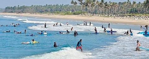 Tourists enjoy the summer day surfing at Vettakkada beach in Varkala