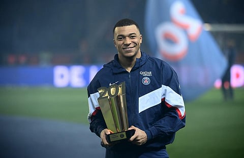 Paris Saint-Germain's French forward Kylian Mbappe poses with a trophy at the end of a ceremony after he became PSG's all-time top scorer with his 201st goal for the club. (Photo | AFP)