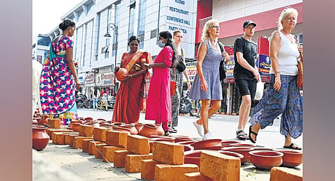 Foreign tourists walk past pots and bricks kept for sale for the Attukal Pongala festival in Thiruvananthapuram | Vincent Pulickal