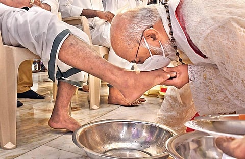FILE: Cardinal Mar George Alencherry kisses the foot of a parishioner during the Maundy Thursday service at St Mary’s Cathedral Basilica, March 2021.