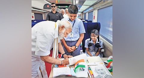 Prime Minister Narendra Modi signs paintings and essays by students, on board the Vande Bharat Express at Thiruvananthapuram Central Station on Tuesday | PTI