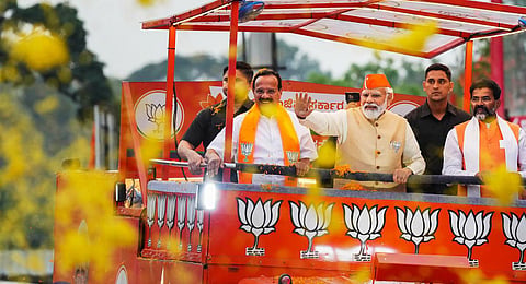 Prime Minister Narendra Modi waves at crowd during a roadshow in support of BJP candidates for upcoming Assembly polls, in Bengaluru.(Photo | PTI)