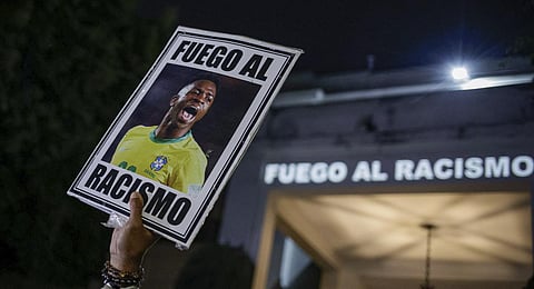 A protester holds up a photo of Brazilian star Vinicius Jr and a message that reads in Portuguese; 'Fight racism' during a protest against racism in Sao Paulo, Brazil, May 23, 2023. (Photo | AP)