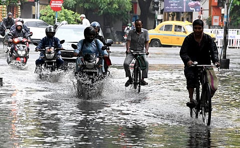 Commuters wade through a waterlogged road after rainfall, in Kolkata, Wednesday, June 28, 2023. (Photo | PTI)
