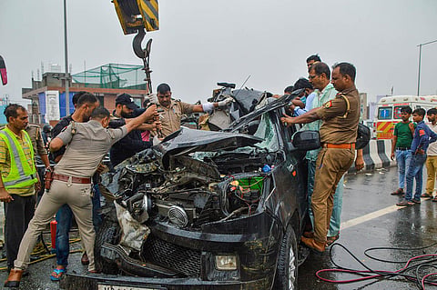 Police personnel and others near the wreckage of a car after a head-on collision with a bus on Ghaziabad-Meerut Expressway, in Ghaziabad.