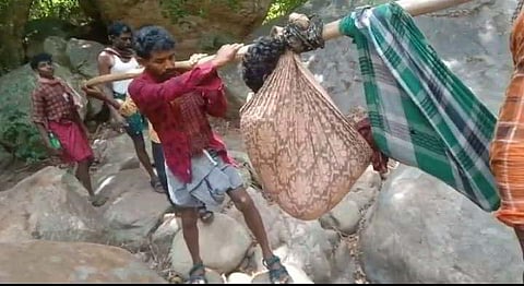 Tribals carry a 30-year-old man in a cradle from Kurumalai tribal settlement to Udumalai Government Hospital