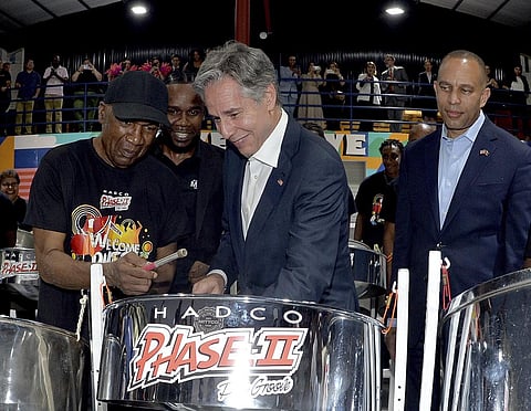 United States Secretary of State Antony Blinken, center, plays a steel pan accompanied by musician Len 'Boogsie' Sharpe. (Photo | AP)