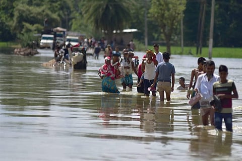 In this June 2023 representational image, villagers wade through a flooded road after heavy rainfall in Hojai district of Assam. (Photo | PTI)