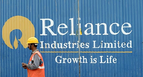 FILE - A worker walks past the signage of Reliance Industries Limited (RIL) in Mumbai. (Photo | AFP)