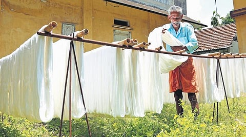 Ratnan K P (Kuttan), who has been working in the handloom sector for nearly five decades, hanging bleached yarn for drying in the sun. (Photo | T P Sooraj)