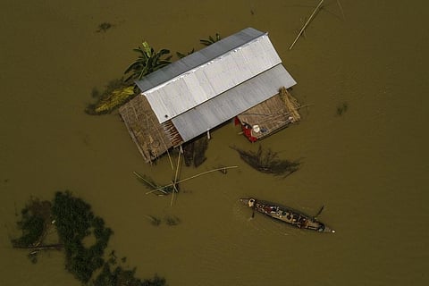 Residents leave their submerged house on a boat in Sandahkhaiti, a floating island village in the Brahmaputra River in Morigaon district, Assam, Aug. 30, 2023. (Photo | AP)