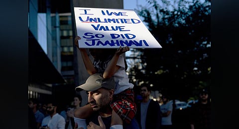 A girl sits atop her father's shoulders while holding a sign for Jaahnavi Kandula, during a protest in Seattle, after the footage of a cop joking about her death came to light. (Photo | AP)