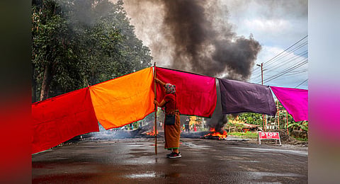 A woman protester blocks a road during a 48-hour general strike in Imphal on Sept 19, 2023, as they demand restoration of peace in Manipur after ethnic violence. (Photo | AFP)
