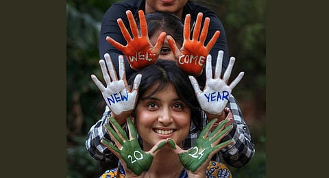 Youngsters with their hands painted in tricolour pose for photographs, as celebrations to welcome 2024 break out on the eve of the New Year on the streets across the country on Sunday (PTI)
