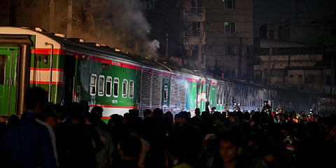 Crowds gather as Bangladeshi fire fighters search the burnt out carriages of the Benapole Express in Dhaka on January 5, 2024. (Photo | AFP)
