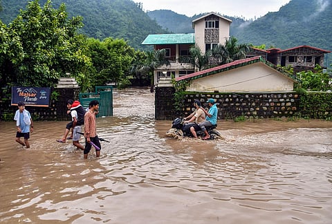 Commuters on a waterlogged road in Dehradun.