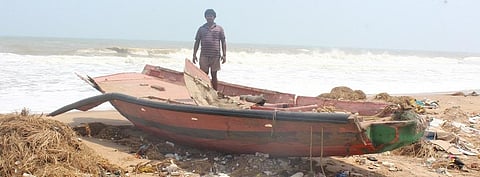A fisherman stands near his damaged boat in Penthakata village. Photo: Ashis Senapati