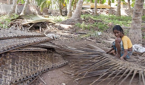 A woman from the indigenous community weaves mat of coconut leaves in Kovalam. Photo: Getty Images