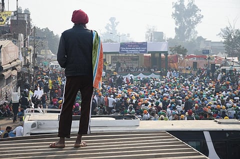 दिल्ली-सिंघु बॉर्डर पर आंदोलन कर रहे किसानों के मंच को निहारता एक किसान। फोटो: धनंजय
