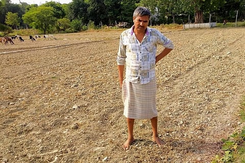 Phoolchandra Maurya, a farmer in UP's Prayagraj district, stands in his dry field. Photo: Aryan Kapoor