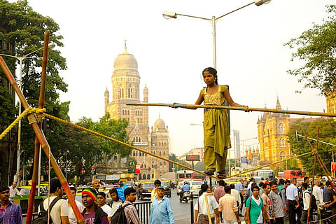 शिक्षा से दूर अपना और अपने परिवार का पेट भरने के लिए मुंबई की सड़कों पर तमाशा दिखाती बच्ची; फोटो: आईस्टॉक