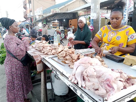 Vendors slice pieces of roast chicken ready to sell at Kariakoo business hub in Dar es Salaam, Tanzania