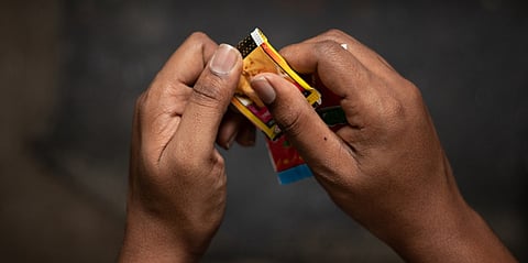 Close up of a man hand tearing a packet of chewing tobacco or Gutka
