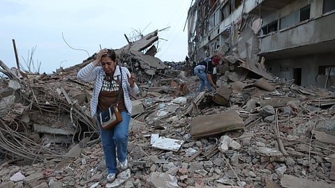Residents walk among the rubble of building damaged in earthquakes the previous day in Catia La Mar, Venezuela