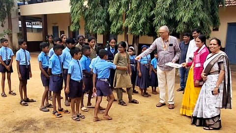 Deputy Director of Animal Husbandry and Veterinary Sciences, A Baburatna distributing sweets to students at higher primary school at Puradal on first day of school reopening in Shivamogga