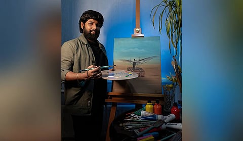 Purnama Chary Kagithala poses with one of his paintings, Dream of Paradisi