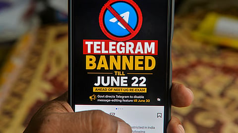 A man checks his mobile phone displaying information related to the temporary restriction on the messaging application Telegram ahead of NEET re-test