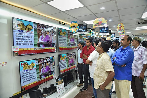 People watch Finance Minister Nirmala Sitharaman tabling the Union Budget 2019-20 on TV sets at a showroom in Patna (Pic: PTI)